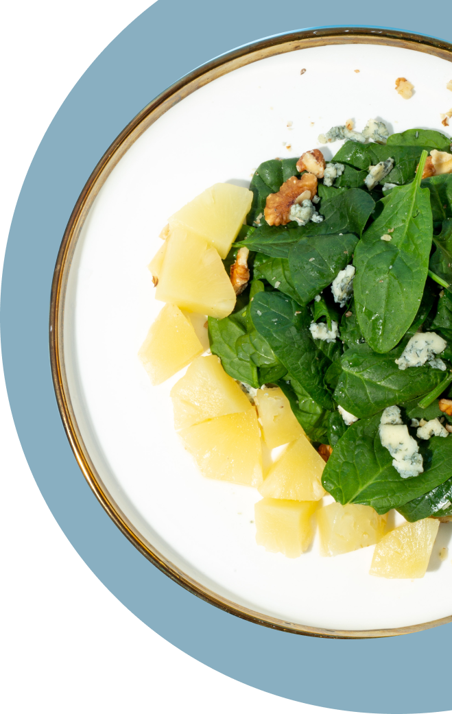 A plate of salad with pineapple and spinach